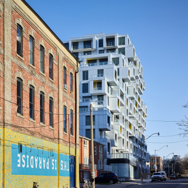 Morning sun accentuates the boxed balcony volumes, as seen looking north from Queen St. West. Photo by Scott Norsworthy.