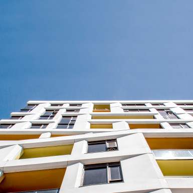 Detail view from street looking up at angled precast concrete details, and recessed balcony walls / Marine de Carbonnieres