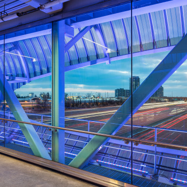 Interior view of the bridge toward Highway 401. The sculptural perforated metal scrim acts as a glimmering shading device during the day and as a glowing line of coloured light over the highway at night. Photo by Michael Muraz.
